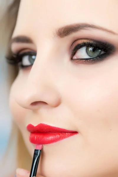 Maquillaje artista aplicando lápiz labial rojo en los labios de la mujer —  Fotos de Stock