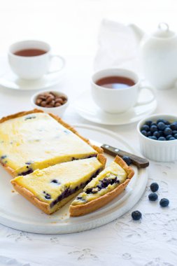 Çay saati. Ev yapımı yaban mersinli cheesecake, bardak çay, fındık ve berry beyaz masa örtüsü