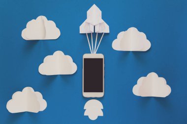 Başlamak yukarıya ya da bağlantı kavramı hızlı. Mavi gökyüzü bulutlar ile akıllı telefon ile denize indirmek kağıt roket. Origami. Kağıt kesiği. Üstten görünüm. Tonda