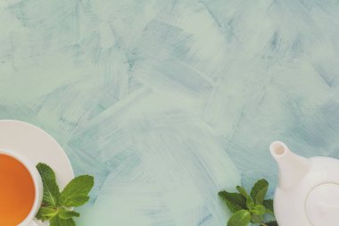 Çay kavramı. Çaydanlık ve bardak yeşil bitki çayı ile nane yaprakları ahşap zemin üzerine dekore edilmiştir. Üstten Görünüm. Uzay kopyalayın. Düz yatıyordu. Tonda