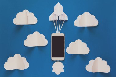 Başlamak yukarıya ya da bağlantı kavramı hızlı. Mavi gökyüzü bulutlar ile akıllı telefon ile denize indirmek kağıt roket. Origami. Kağıt kesiği. Üstten görünüm. Tonda