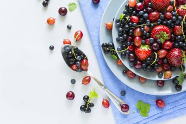 Çilek, yaban mersini, kiraz, Bektaşi üzümü ve ahşap gri arka plan üzerinde siyah frenk üzümü meyve salatası. Düz yatıyordu. Üstten görünüm