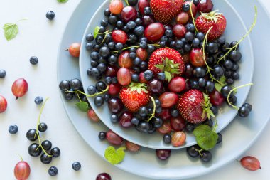 Çilek, yaban mersini, kiraz, Bektaşi üzümü ve ahşap gri arka plan üzerinde siyah frenk üzümü meyve salatası. Düz yatıyordu. Üstten görünüm