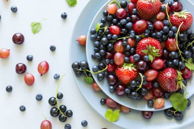 Çilek, yaban mersini, kiraz, Bektaşi üzümü ve ahşap gri arka plan üzerinde siyah frenk üzümü meyve salatası. Düz yatıyordu. Üstten görünüm