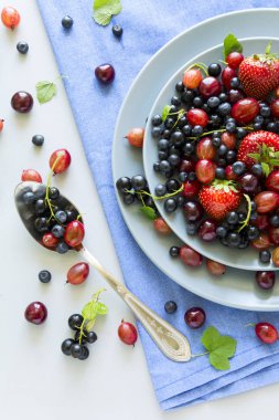 Çilek, yaban mersini, kiraz, Bektaşi üzümü ve ahşap gri arka plan üzerinde siyah frenk üzümü meyve salatası. Düz yatıyordu. Üstten görünüm