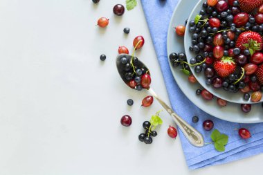 Çilek, yaban mersini, kiraz, Bektaşi üzümü ve ahşap gri arka plan üzerinde siyah frenk üzümü meyve salatası. Düz yatıyordu. Üstten görünüm