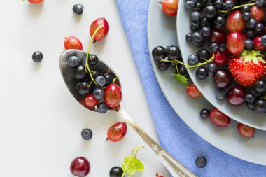 Çilek, yaban mersini, kiraz, Bektaşi üzümü ve ahşap gri arka plan üzerinde siyah frenk üzümü meyve salatası. Düz yatıyordu. Üstten görünüm