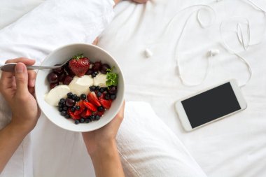 Sağlıklı beslenme kavramı. Kadınların elleri süzme peynir krem, çilek, kiraz, Bektaşi üzümü ve yaban mersini ile bir kase tutarak. Üstten görünüm. Yaşam tarzı