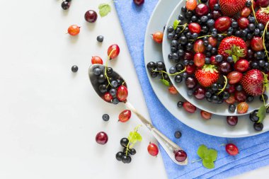 Çilek, yaban mersini, kiraz, Bektaşi üzümü ve ahşap gri arka plan üzerinde siyah frenk üzümü meyve salatası. Düz yatıyordu. Üstten görünüm