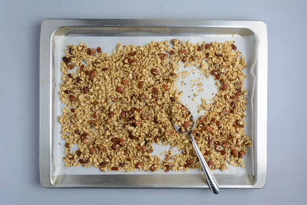 Homemade granola from oatmeal, applesauce, honey, oil, almond, walnut, raisin, flax and sesame seeds on baking sheet. Flat lay. Top view.