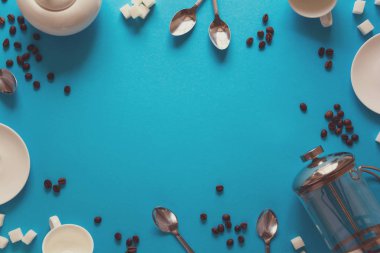 Çeşitli kahve aksesuarları yapma: Fransızca kahve basın, bardaklar, tabaklar, kahve çekirdekleri, kaşık ve şeker mavi Kağıt arka plan üzerinde. Günaydın kavramı. Kopya için alan. Üstten görünüm. Düz yatıyordu. Tonda
