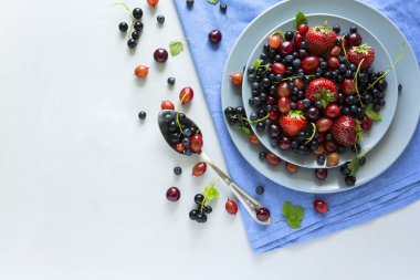 Çilek, yaban mersini, kiraz, Bektaşi üzümü ve ahşap gri arka plan üzerinde siyah frenk üzümü meyve salatası. Düz yatıyordu. Üstten görünüm