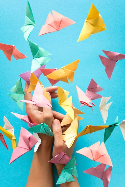 Ruh sağlığı kavramı. Renkli kağıt kadının elleri üzerinde oturan ve uçan kelebekler. Uyum duygu. Origami. Tarzı kağıt kesme.