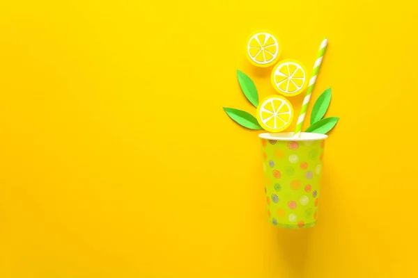 Summer drink with paper cut lemon slices and leaves on yellow paper background. Summer drink concept. Top view. Flat lay