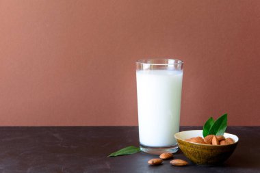 Badem sütü ile badem kahverengi ahşap bir masa üzerinde. Sağlıklı beslenme kavramı.