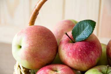 Kırmızı ve yeşil elma ön tarafındaki kahverengi ahşap duvar ahşap sepetle. Hasat kavramı