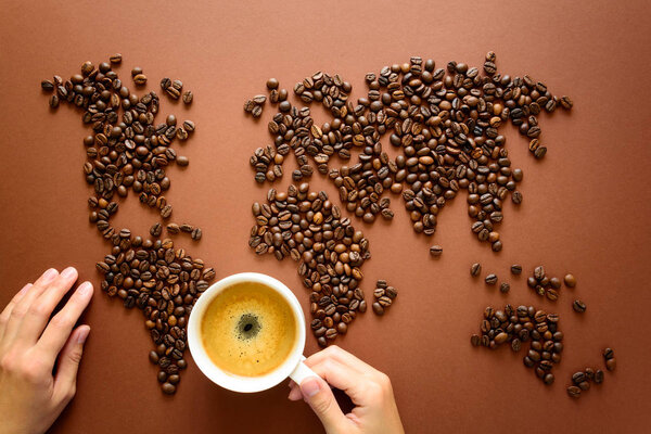 Map of the world made of roasted arabica coffee beans on brown paper background. International coffee industry or travel planning concept