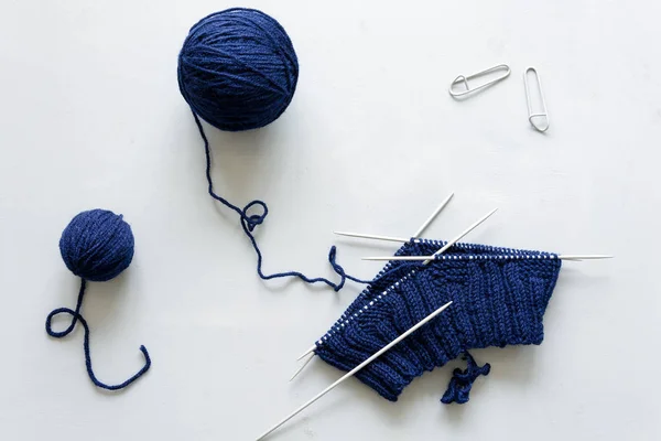 女孩编织蓝色帽子针织针在灰色的木质背景 针织工艺 顶部视图 — 图库照片