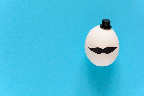 白鸡蛋与纸胡子和圆筒在蓝色纸背景 剪掉样式 Movember — 图库照片