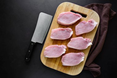 Koyu ahşap arka plan üzerinde yemek pişirmek için malzemelerle Çiğ domuz. Üstten görünüm. Kopya alanı.