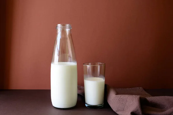 Milk bottle and milk glass on brown paper background. Healthy eating concept