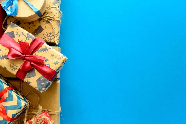 クリスマス プレゼントに平面図は 青紙の背景にリボンで飾られたギフトの紙に包まれて 年始の休日のお祝いの装飾の概念 領域をコピーします フラットを置く — ストック写真