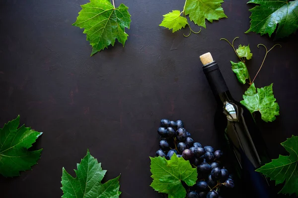Bir şişe kırmızı şarap, üzüm ve koyu ahşap arka plan üzerinde yalan yaprak. Üstten görünüm. Düz yatıyordu. Kopya alanı