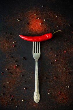 Ham Olgun kırmızı biber biber biber bezelye ve koyu ahşap arka plan üzerinde yalan toz çatalla üzerinde. Üstten görünüm. Düz yatıyordu