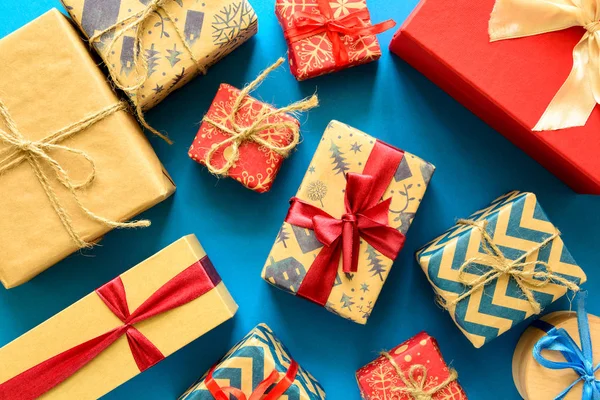 Üstten görünüm Noel hediyeleri üzerinde şerit mavi Kağıt arka plan üzerinde süslenmiş hediye kağıt sarılı. Yeni yıl, tatil ve kutlama süslemeleri kavramı. Uzay kopyalayın. Düz yatıyordu