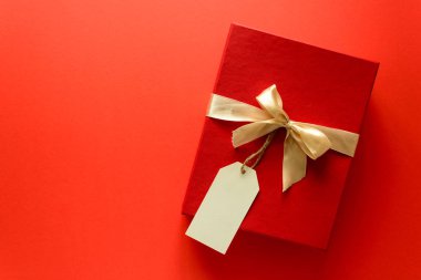 Üstten görünüm kırmızı Noel hediye kutusu üzerinde şerit üzerinde kırmızı Kağıt arka plan ile dekore edilmiştir. Yeni yıl, tatil ve kutlama süslemeleri kavramı. Uzay kopyalayın. Düz yatıyordu. Mock-up