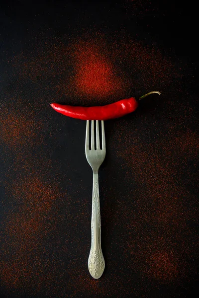 Ham Olgun kırmızı biber biber biber bezelye ve koyu ahşap arka plan üzerinde yalan toz çatalla üzerinde. Üstten görünüm. Düz yatıyordu