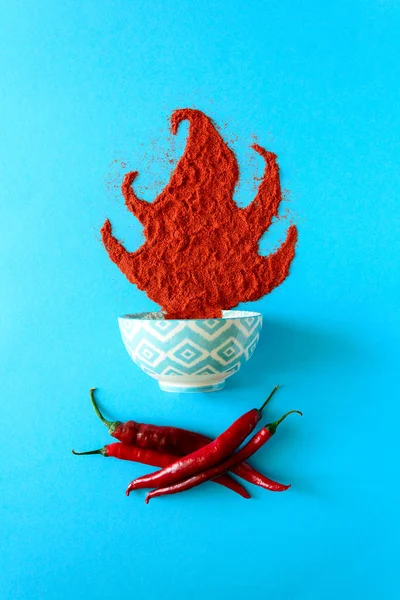 Mavi Kağıt arka plan üzerinde yalan şenlik ateşi formunda kırmızı biber tozu. Üstten görünüm. Düz yatıyordu