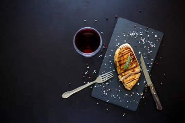 Biberiye, şarap ve koyu ahşap zemin üzerine baharat ile kayrak tabakta tavuk fileto ızgara. Üstten görünüm. Düz yatıyordu. Kopya alanı