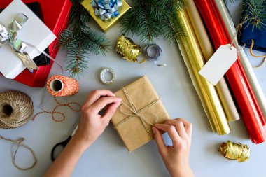 Kadının elleri gri ahşap arka plan üzerinde mevcut kutu süslemeleri. Yeni yıl ve Noel süslemeleri kavramı.