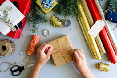 Kadının elleri gri ahşap arka plan üzerinde mevcut kutu süslemeleri. Yeni yıl ve Noel süslemeleri kavramı.