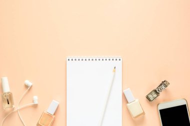 Kadınsı çalışma alanı ile smartphone, kulaklık, defter, kalem, tırnak cilası ve saat. Düz yatıyordu. Üstten görünüm. Kopya alanı