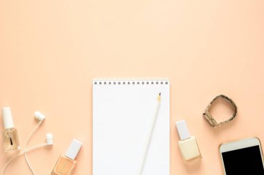 Kadınsı hızı smartphone, kulaklık, defter, kalem, tırnak cilası ve saat ile çalışır. Düz yatıyordu. Üstten görünüm. Kopya alanı