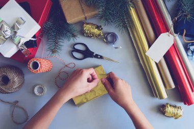 Kadının elleri gri ahşap arka plan üzerinde mevcut kutu süslemeleri. Yeni yıl ve Noel süslemeleri kavramı. Tonda