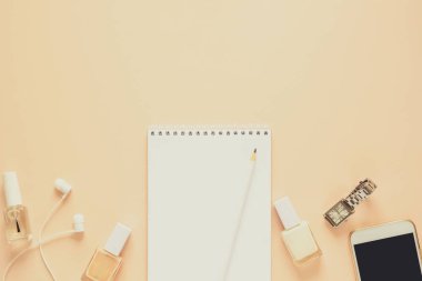 Kadınsı çalışma alanı ile smartphone, kulaklık, defter, kalem, tırnak cilası ve saat. Düz yatıyordu. Üstten görünüm. Uzay kopyalayın. Tonda
