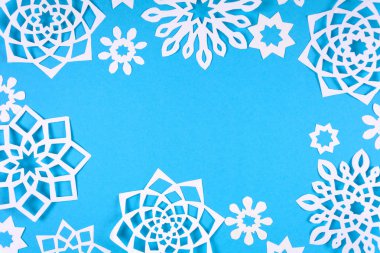 Mavi arka plan üzerinde kağıt kar taneleri. Üstten görünüm. Noel dekorasyon