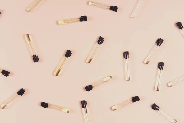 Parfüm örnekleri ve pembe bir arka plan üzerinde beyaz çiçekler. Üstten görünüm. Uzay kopyalayın. Tonda