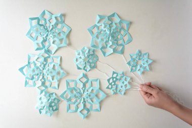 Holding Kağıt mavi kar taneleri (balon) ile beyaz arka plan üzerinde döşeme iplik ver. Üstten görünüm. Noel dekorasyon