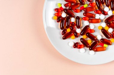 Renkli kapsül ve hapları pembe bir arka plan üzerinde plaka üzerinde. Sağlık ya da sentetik Gıda kavramı. Üstten görünüm