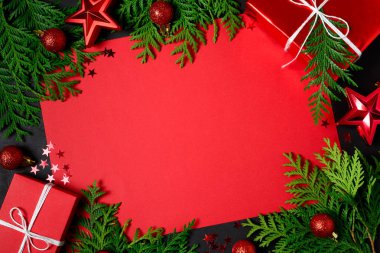 Kırmızı hediye kutuları, çam dalları, konfeti, kağıt, metin ve siyah arka plan üzerine oyuncaklar Noel çerçeve. Düz yatıyordu. Üstten görünüm. Kopya alanı
