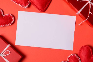 Keçe sevgi kalpleri ve tebrik kartı kırmızı Kağıt arka plan üzerinde mevcut kutusu. Sevgililer günü kutlama kavramı. Üstten görünüm. Düz yatıyordu.