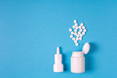 Tıbbi elektronik termometre, ilaç şişe hap ve sprey için burun üzerinde mavi arka plan ile. Sağlık kavramı. Üstten görünüm. Uzay kopyalayın. Düz yatıyordu