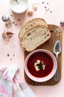 Ekşi krema, ekmek, sarımsak ve baharat pembe bir arka plan üzerinde pembe kase kırmızı pancar çorbası çorba. Üstten görünüm. Düz yatıyordu