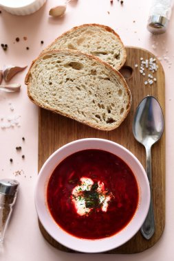 Ekşi krema, ekmek, sarımsak ve baharat pembe bir arka plan üzerinde pembe kase kırmızı pancar çorbası çorba. Üstten görünüm. Düz yatıyordu