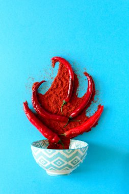 Kağıt arka plan mavi ham Olgun kırmızı biber biber bezelye ve biber tozu yatan şenlik ateşi formunda. Üstten görünüm. Düz yatıyordu