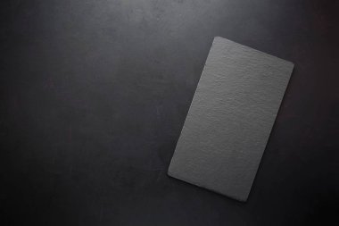 Üstten görünüm rustik koyu arka plan üzerinde siyah dikdörtgen kayrak tabakta. Uzay kopyalayın. Tonda